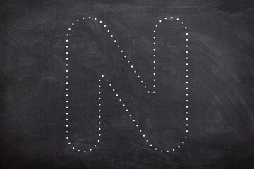 Uppercase tracing letter N set on chalkboard. Teacher font trace letter black and white isolated on black background. Kindergarten tracing letter worksheet