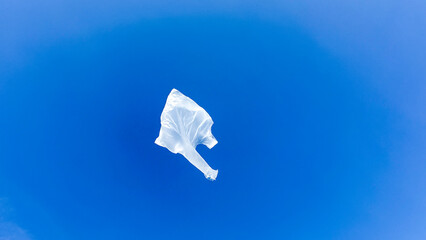 Floating ghostly plastic bag dances in azure sky, invoking Plastic Free July and World Environment Day awareness