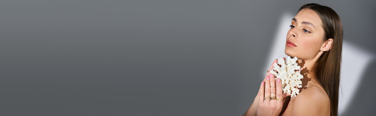 Summer vibes with a beautiful young woman elegantly posing with flowers in a minimalist setting