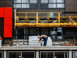 Fototapeta premium Bricklayer at construction site of modern building