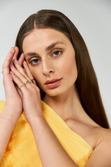 Naklejka premium Elegant young woman radiating beauty while posing in soft sunlight with a vibrant summer dress