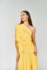 Stunning young woman in a vibrant yellow dress embodies summer fashion trends