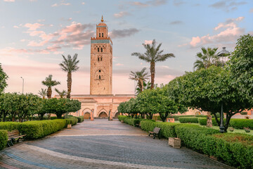 Fototapeta premium The majestic Koutoubia Mosque stands tall amidst a serene garden in Marrakech, bathed in the warm glow of the setting sun