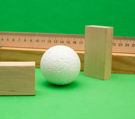 Still life with wooden blocks and a a plastic foam ball on green background	