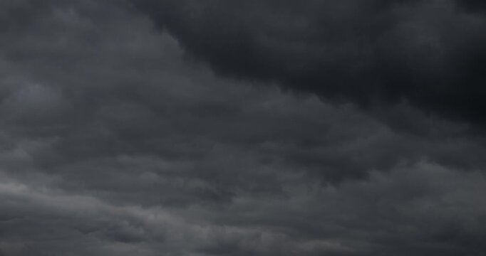 Dense black clouds covered the sky and are flying. Weather change to storm and hurricane with rain.