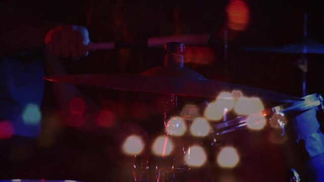 drum cymbal being struck in dark performance, with flickering bokeh lights glowing in flat design