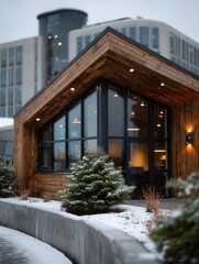 Modern wooden house with large glass windows in winter snowy setting with small snow-covered trees