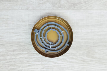Rolled up flea and tick collar for dogs in a tin open can on a white wooden floor. Top view.