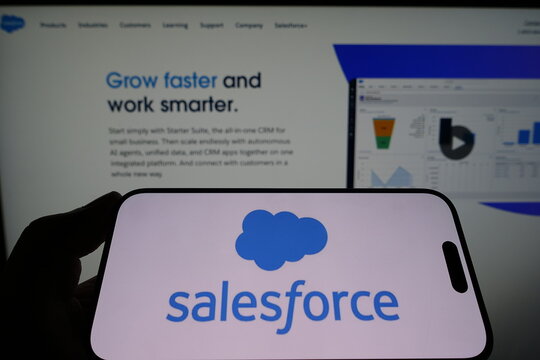 Kiel, Germany - 05-15-2025: Person holding smartphone with Salesforce logo on screen in front of the companys website Focus on the phone display Unmodified photo