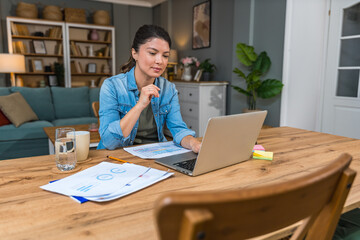 Young freelance business woman having video call conference on laptop computer while sitting and...