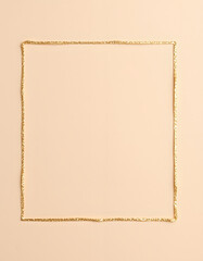 Obraz premium Shimmering gold (bronze) sparkle empty border on soft beige-gray paper backdrop. Minimalist open space pattern., photo. with white shades