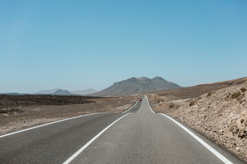 Driving on a scenic road in Fuerteventura with mountains in the distance