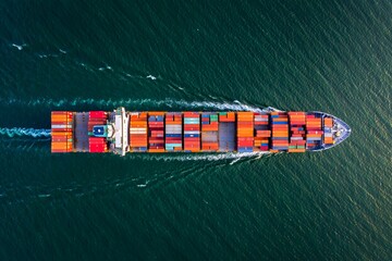 Cargo container ship at sea near port with cranes and stacked containers