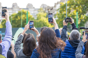 Plakat Crowd of people raising smartphones and cameras to capture outdoor media event. Mobile or citizen journalism concept.
