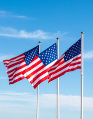 Obraz premium A simple trio of stars and stripes flags blowing in the wind against a clear blue sky