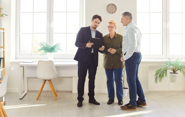 Fototapeta premium Attentive senior couple tours a new property with a real estate agent, discussing potential purchase or rental options. The visit highlights interest in real estate and future homeownership.