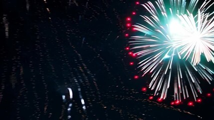 Exploding fireworks lighting up the night sky with vibrant red and white flashes, creating a festive atmosphere for celebration event.