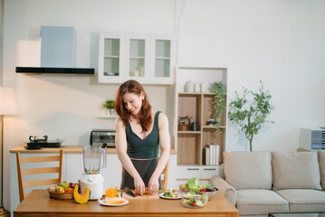 Fit woman enjoys fresh salad, fruits, and juice in a modern kitchen, showcasing wellness,...