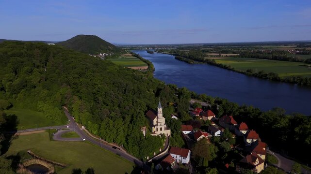 Drone shot of St. Salvator in Donaustauf, Roman Catholic pilgrimage church in Bavaria, Germany. Surrounded by greenery, the Danube, and a picturesque village. Perfect for cultural and travel content. 