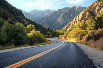 Fototapeta premium Curved road winding through lush green trees and rocky mountains under a bright blue sky with scattered clouds