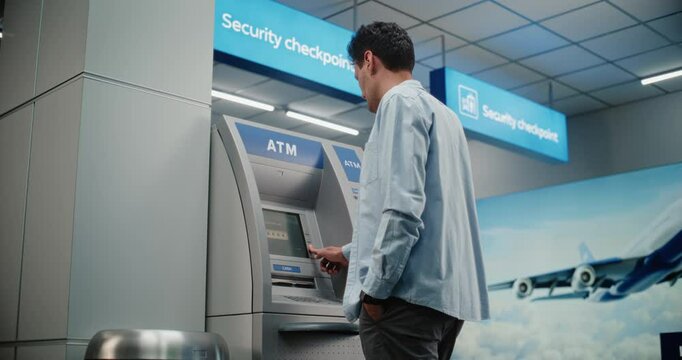Cash Machine in Crowded Airport Terminal: Man Pressing Buttons on ATM Keypad, Entering PIN Code for Cash Withdrawal Transaction, Taking Money. Automated Teller Machine, Banking Services. Medium Shot.