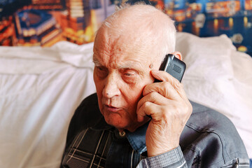 Elderly man engaged in a phone conversation in a comfortable indoor setting at night
