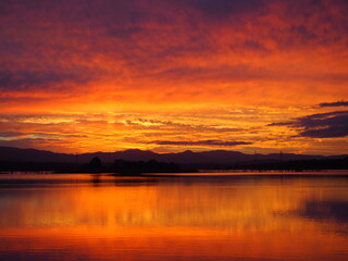 Obraz premium Sunset with golden and rosy clouds in sky and river