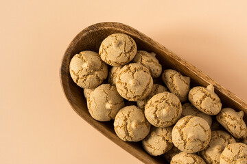 Amaretti cookie in a wooden bowl on a beige background , top view high-resolution  . Delicious , crunchy biscuits for tea .