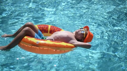 Swimming pool fun with happy kid. Kid splash in pool on summer day. Child rest on inflatable ring in swimming pool. Kid in poolside with floating toy. child with float ring in blue pool. Kids summer