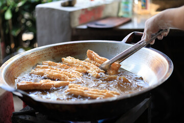 Man Hand Fried Chinese Deep Fried Dough Stick or Youtiao in Big Pan