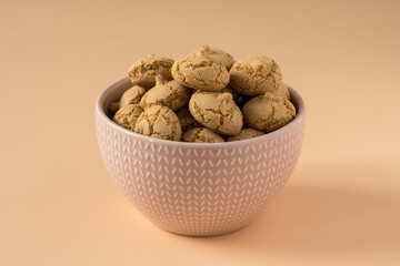 Amaretti cookie in a porcelain bowl on a beige background , side view ,high-resolution  . Delicious , crunchy biscuits for tea .