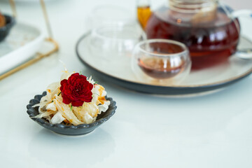Elegant Thai Appetizer with Red Flower Garnish and Glass Teapot in Soft Focus