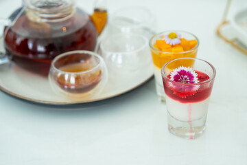 Assorted desserts and teapot with glass cup against marble table background