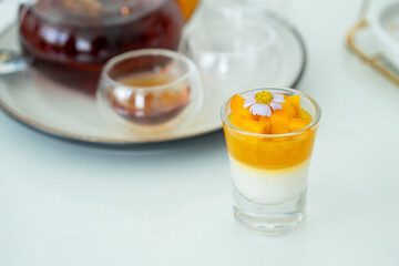 Desserts and teapot with glass cup against marble table background