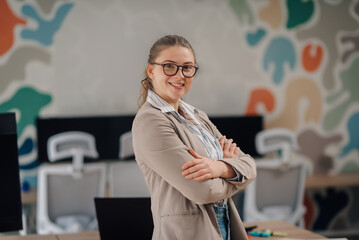 Smiling businesswoman with crossed arms in modern office