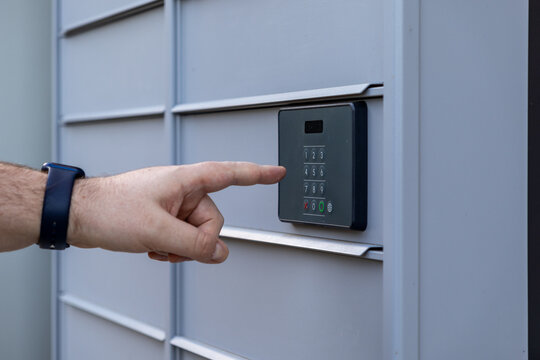 Customer hand touching digital keypad for code entry on automated parcel locker providing secure package delivery access