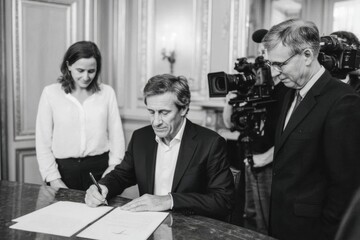 Mature caucasian man signing document with colleagues and camera crew present