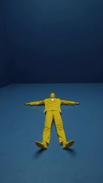 Silhouette en costume jaune allong&eacute;e au sol dans une pi&egrave;ce bleue vide

