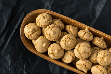 Amaretti cookie in a wooden bowl on a black background , top view , high-resolution . Delicious , crunchy biscuits for tea .