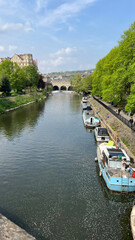 Obraz premium Scenic view of the River Avon with colorful boats and lush greenery in Bath during a sunny day