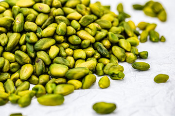 A close-up shot of a pile of fresh, green shelled pistachios.