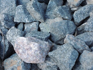 Top view of rough grey granite stones piled together with sharp texture ideal for industrial materials, geology references and construction or background texture use cases