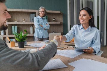 Happy young business woman bank manager handshaking client at meeting. Smiling female hr hiring...