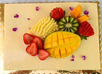 Elegant Pistachio Layer Cake with Tropical Fruit including strawberries, mango, kiwi, and...