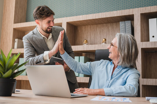 Mature Businesswoman giving hi five touching hands with co worker after finish work and completed the work perfectly, as expected. Happy team giving hight five after successful work