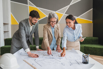Confident engineer team working with Blue Print with architect equipment discussing and planning work flow construction project with partner at the table in office work site.