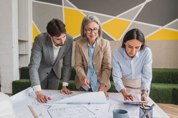 Mid section of diverse male and female architects engineer designer with tablet discussing over a plan at office. Business, engineering, technology and office concept
