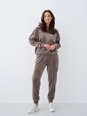 Young woman wearing cozy loungewear in neutral tones against a plain background
