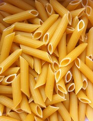 Dry penne pasta background, uncooked pasta