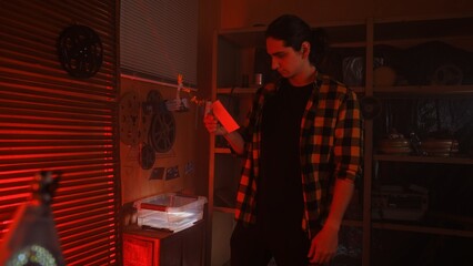 Man Developing Photos in a Darkroom with Red Lighting